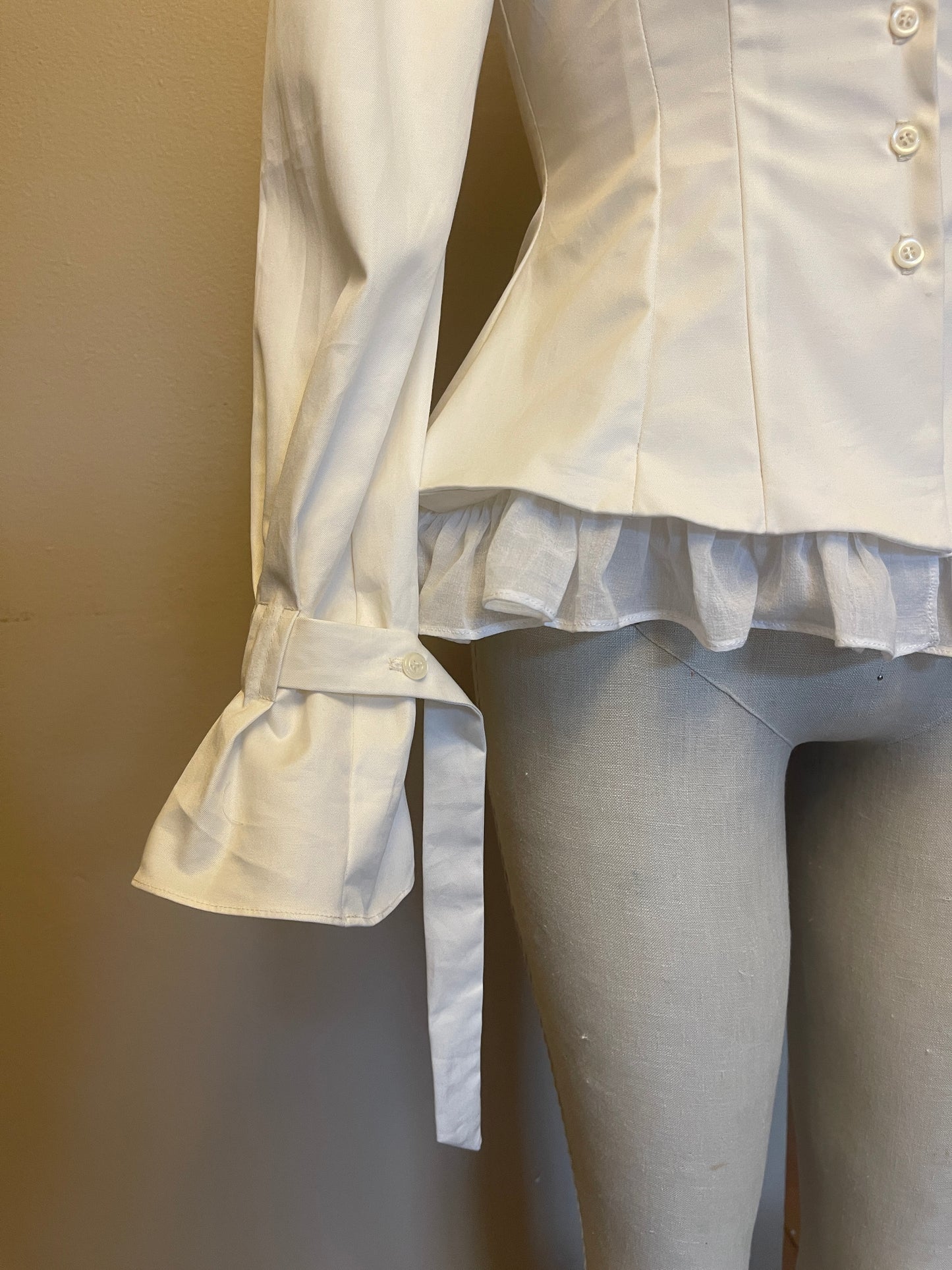 White shirt with ruffle hem and cuffs on a neutral background