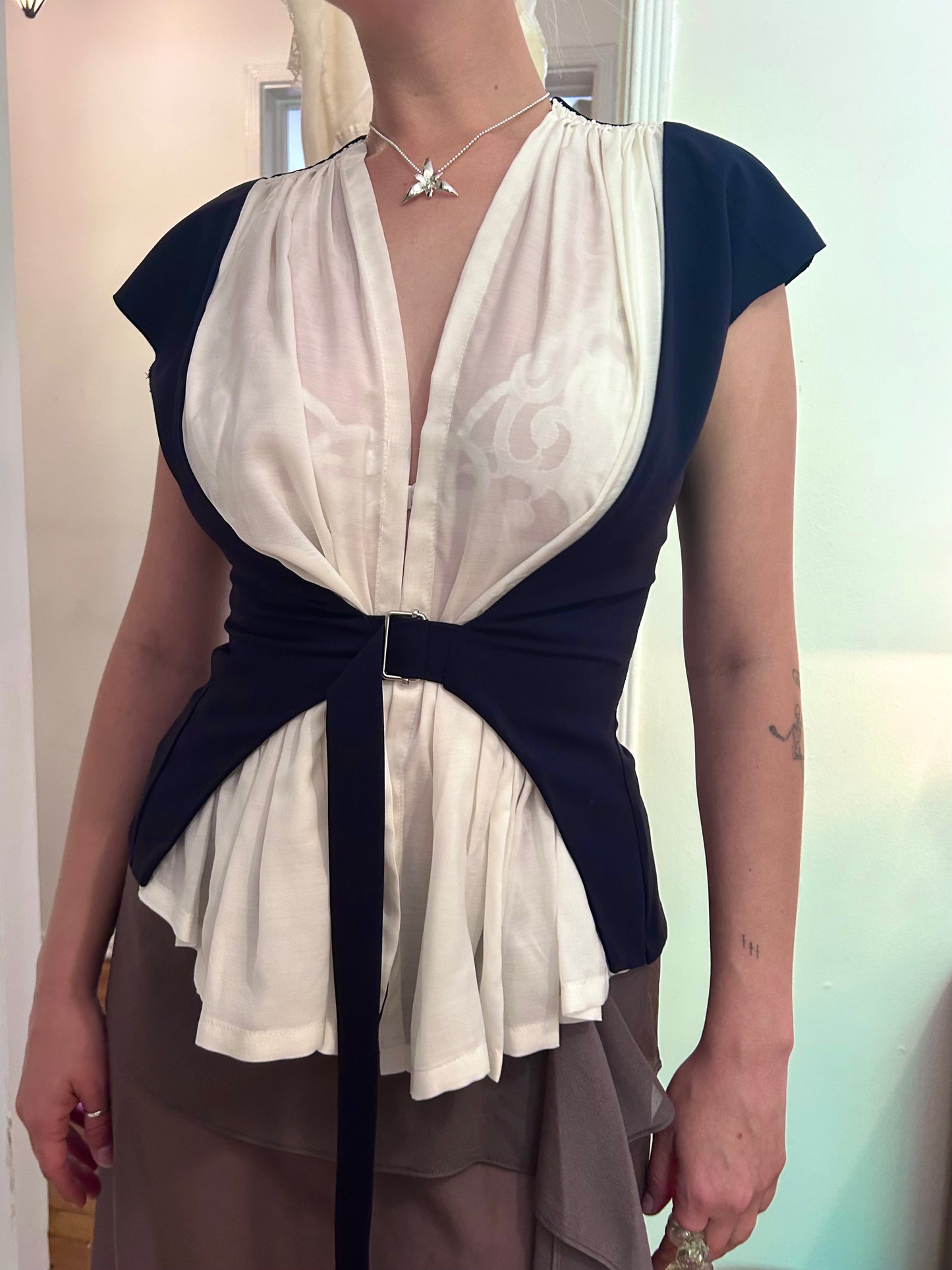 Person wearing a navy and white layered top with a plain background