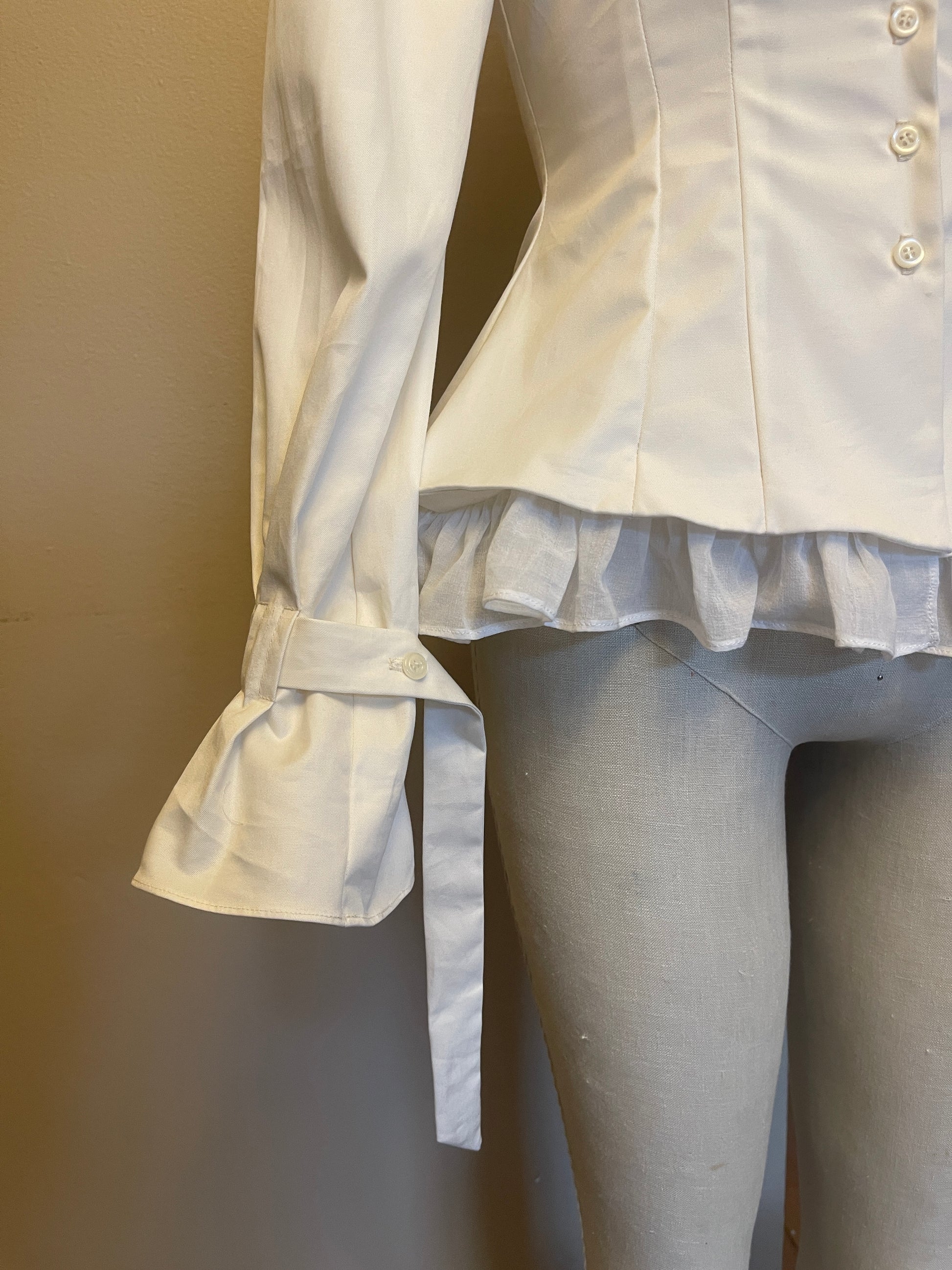 White shirt with ruffle hem and cuffs on a neutral background