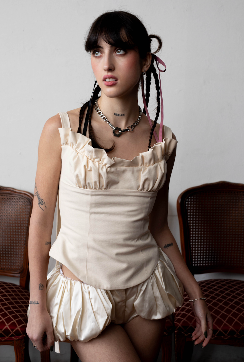 structured, cream, canvas bodice with ruffle trim on the neckline cut on the bias with a curved hem.